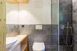 This modern bathroom features a sleek design with dark stone tiles and a wooden vanity.