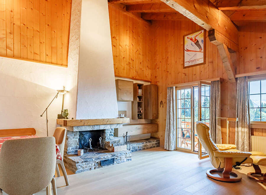 Experience the warmth of this charming chalet-style living space, featuring a stunning stone fireplace and exposed wooden beams.