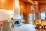 Experience the warmth of this charming chalet-style living space, featuring a stunning stone fireplace and exposed wooden beams.