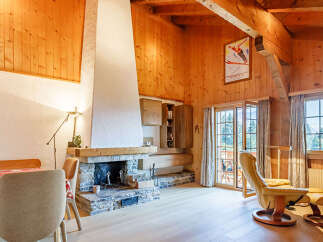 Experience the warmth of this charming chalet-style living space, featuring a stunning stone fireplace and exposed wooden beams.