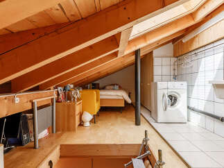 This unique loft space features exposed wooden beams and a cozy bedroom area.