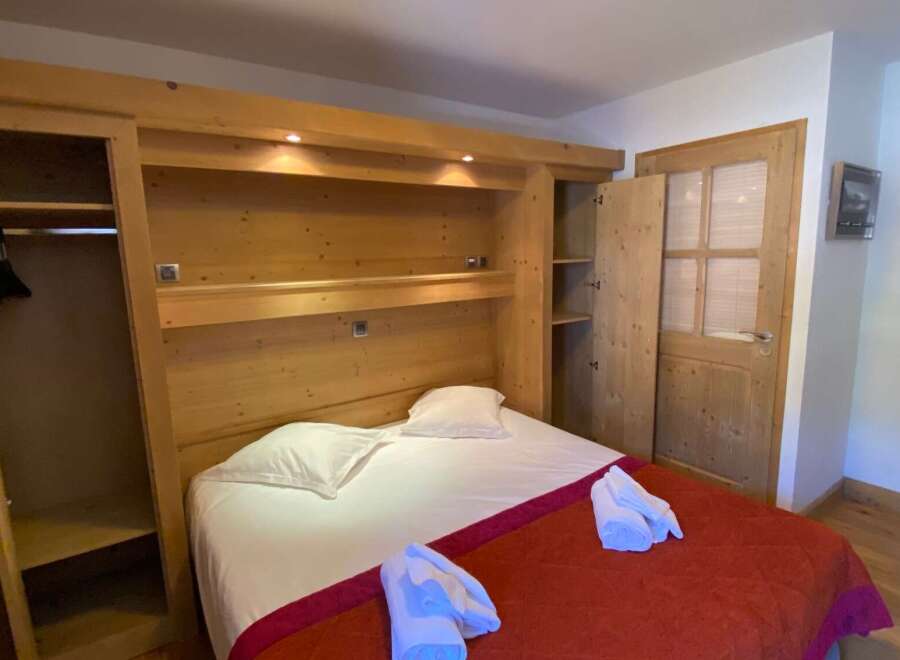 This cozy bedroom features a custom-built wooden headboard with integrated storage and lighting, creating a warm and inviting atmosphere.