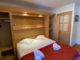 This cozy bedroom features a custom-built wooden headboard with integrated storage and lighting, creating a warm and inviting atmosphere.