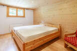 This cozy bedroom features a wooden bed frame and matching wooden paneling, creating a warm and inviting atmosphere.