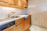 This charming kitchen features warm wooden cabinetry and a sleek countertop, creating a cozy and inviting atmosphere.