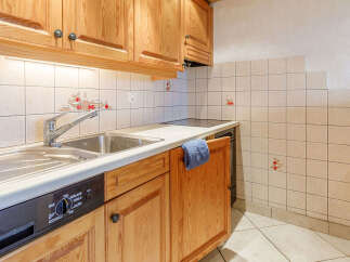 This charming kitchen features warm wooden cabinetry and a sleek countertop, creating a cozy and inviting atmosphere.