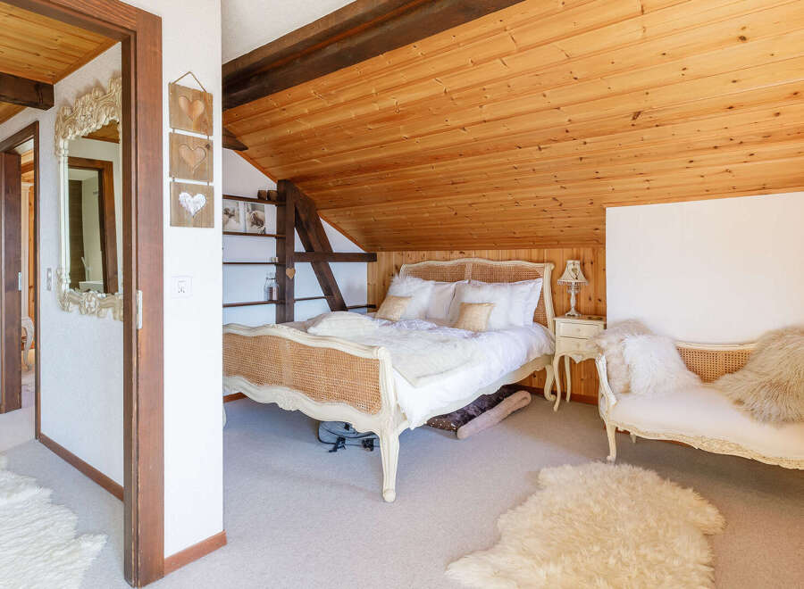 This charming bedroom features a cozy, rustic design with wooden accents and a bright, airy feel.