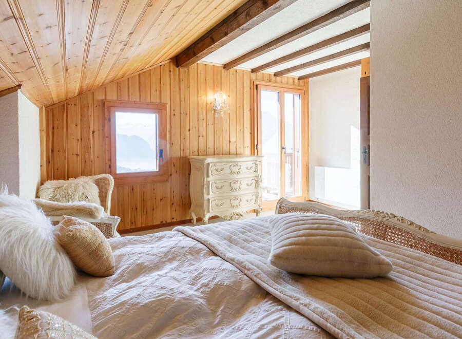 Experience the charm of this cozy bedroom, featuring a warm wooden ceiling and walls that create a serene atmosphere.