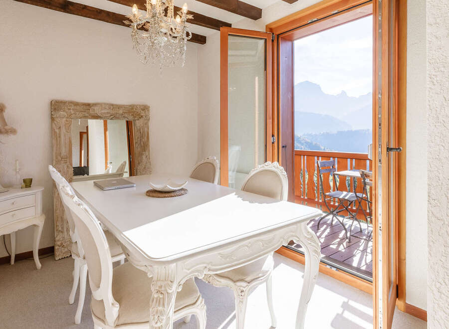 Experience the epitome of elegance in this stunning dining room, featuring a pristine white table and ornate chairs.