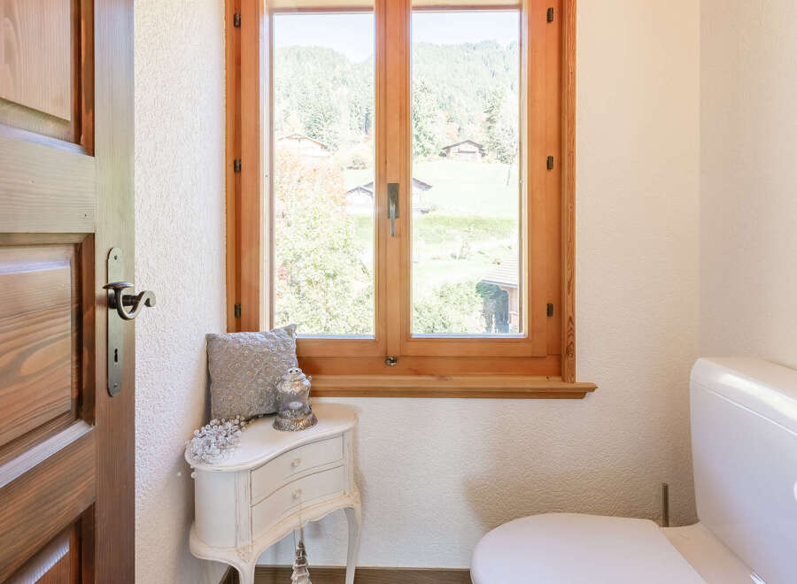 This charming bathroom features a beautiful wooden window that offers stunning views of the surrounding landscape.