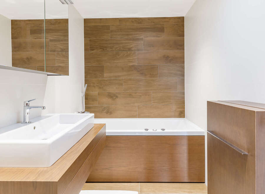 This modern bathroom features a sleek design with a wooden vanity and a luxurious bathtub.