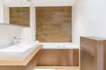 This modern bathroom features a sleek design with a wooden vanity and a luxurious bathtub.
