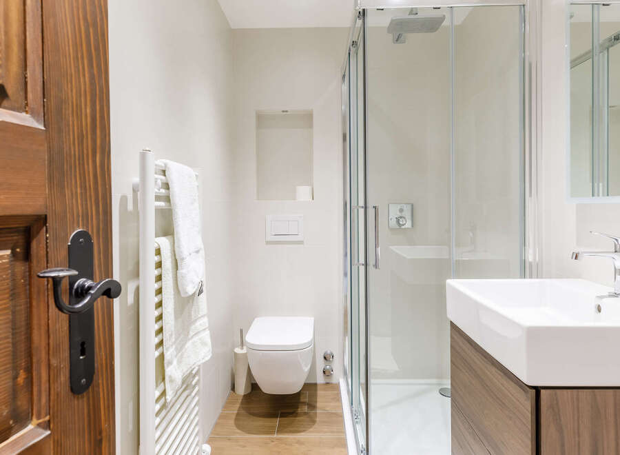 Step into a beautifully designed bathroom featuring a modern shower, sleek sink, and a stylish wooden door.