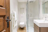 Step into a beautifully designed bathroom featuring a modern shower, sleek sink, and a stylish wooden door.