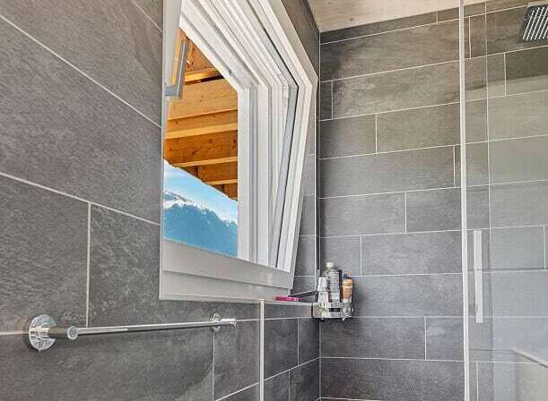 This modern bathroom features a unique design with a tilt-and-turn window, offering both ventilation and natural light.