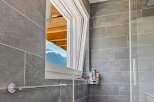 This modern bathroom features a unique design with a tilt-and-turn window, offering both ventilation and natural light.