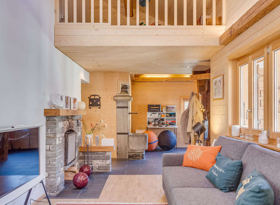 Step into this stunning chalet-style home, boasting a cozy living area with a stone fireplace and a modern TV.