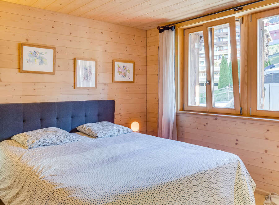 This cozy bedroom features a wooden paneled wall and a comfortable bed with a patterned duvet.