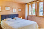 This cozy bedroom features a wooden paneled wall and a comfortable bed with a patterned duvet.
