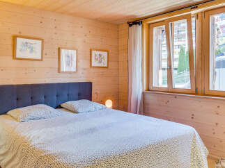 This cozy bedroom features a wooden paneled wall and a comfortable bed with a patterned duvet.