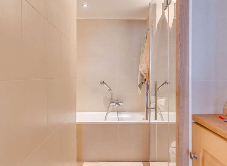 Step into a serene bathroom oasis, featuring a sleek glass shower enclosure and a luxurious bathtub.