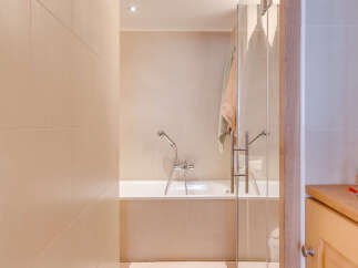Step into a serene bathroom oasis, featuring a sleek glass shower enclosure and a luxurious bathtub.