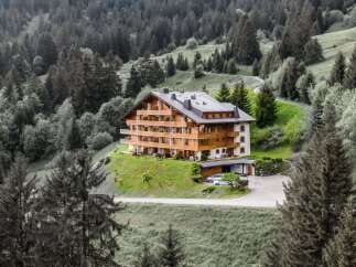 Nestled in a serene mountain landscape, this stunning property boasts a luxurious wooden facade and multiple balconies, offering breathtaking views.
