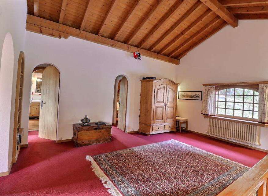 Step into a charming space with this inviting room, featuring a warm wooden ceiling and a vibrant red carpet.