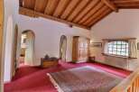 Step into a charming space with this inviting room, featuring a warm wooden ceiling and a vibrant red carpet.