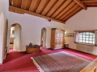 Step into a charming space with this inviting room, featuring a warm wooden ceiling and a vibrant red carpet.