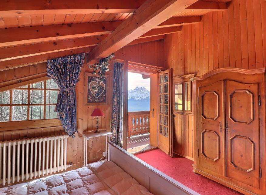 Experience the charm of this cozy bedroom with its warm wooden accents and stunning mountain views.