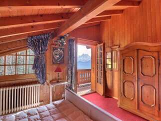 Experience the charm of this cozy bedroom with its warm wooden accents and stunning mountain views.