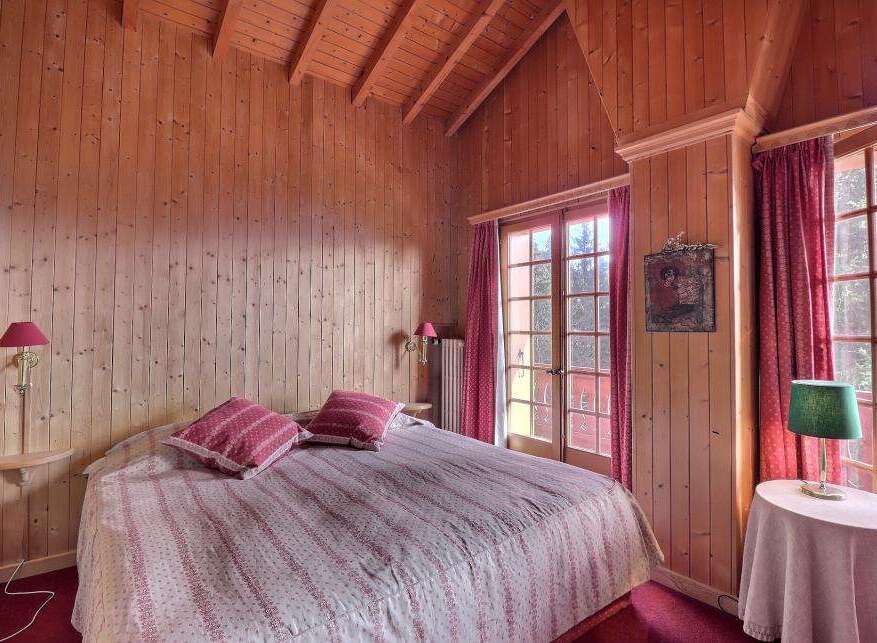 Step into a cozy bedroom retreat with charming wooden paneling and a warm, inviting ambiance.