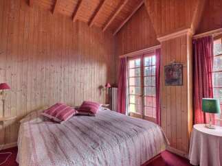 Step into a cozy bedroom retreat with charming wooden paneling and a warm, inviting ambiance.