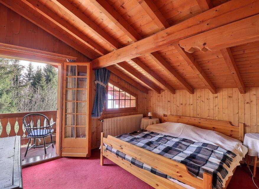 This charming bedroom features a cozy wooden interior with exposed beams and a warm, inviting atmosphere.