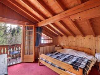 This charming bedroom features a cozy wooden interior with exposed beams and a warm, inviting atmosphere.