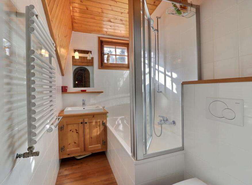 This charming bathroom features a cozy wooden ceiling and a bright, inviting atmosphere.