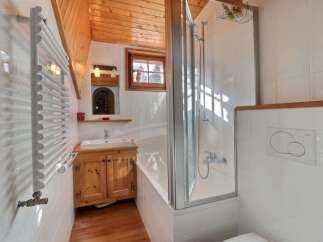 This charming bathroom features a cozy wooden ceiling and a bright, inviting atmosphere.