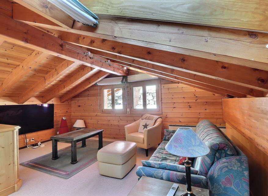 This cozy attic space features a warm, inviting atmosphere with its wooden paneling and exposed beams.