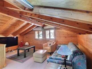This cozy attic space features a warm, inviting atmosphere with its wooden paneling and exposed beams.