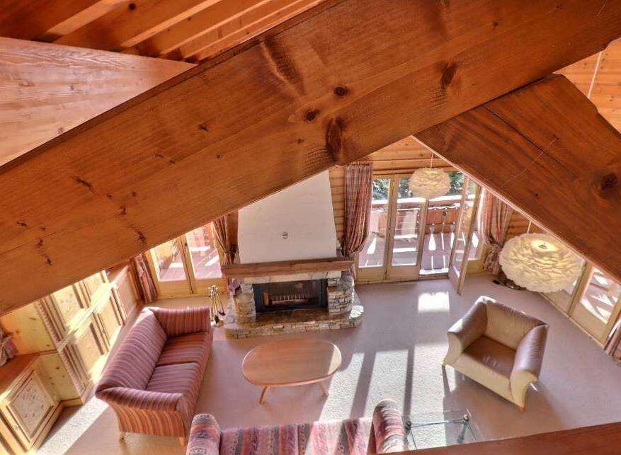 Experience the charm of this cozy chalet, featuring a stunning stone fireplace and exposed wooden beams that create a warm and inviting atmosphere.