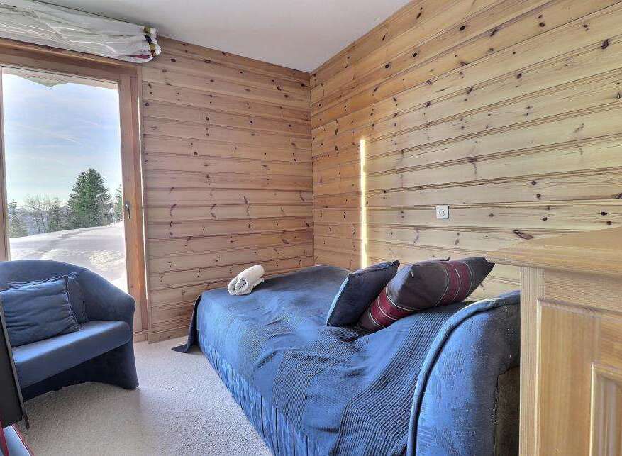 Cozy bedroom featuring wood-paneled walls and a comfortable bed.
