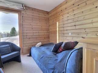 Cozy bedroom featuring wood-paneled walls and a comfortable bed.