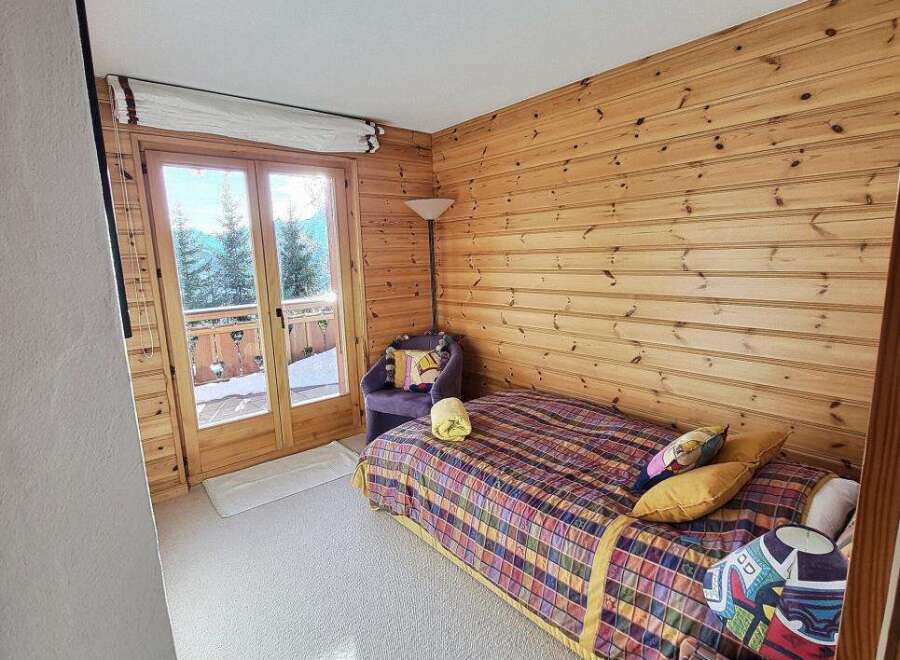 Discover the charm of this cozy bedroom, featuring stunning wood paneling and a vibrant, patterned bedspread.