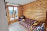 Discover the charm of this cozy bedroom, featuring stunning wood paneling and a vibrant, patterned bedspread.