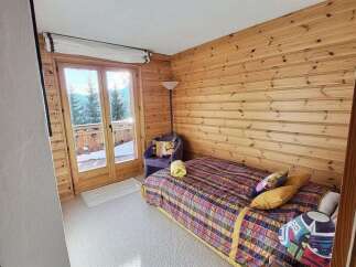 Discover the charm of this cozy bedroom, featuring stunning wood paneling and a vibrant, patterned bedspread.