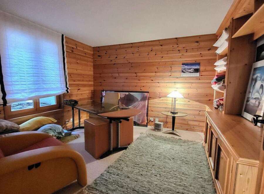 Discover the charm of this cozy home office, featuring warm wood paneling and a stylish desk.