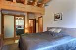 This cozy bedroom features a rustic design with wooden beams and a comfortable bed.