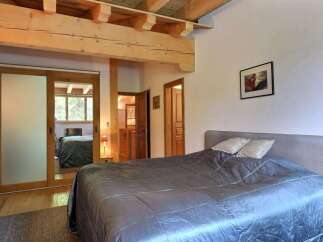 This cozy bedroom features a rustic design with wooden beams and a comfortable bed.