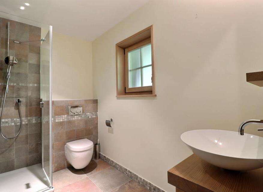 This modern bathroom features a sleek shower, a stylish vessel sink, and a comfortable toilet.